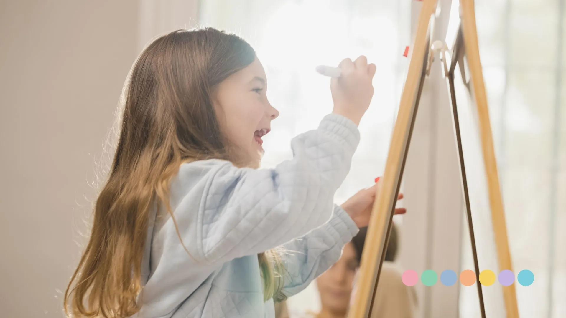 Devojčica crta na tabli uz podršku odrasle osobe – razbijanje mitova o autizmu kroz edukaciju i razumevanje.