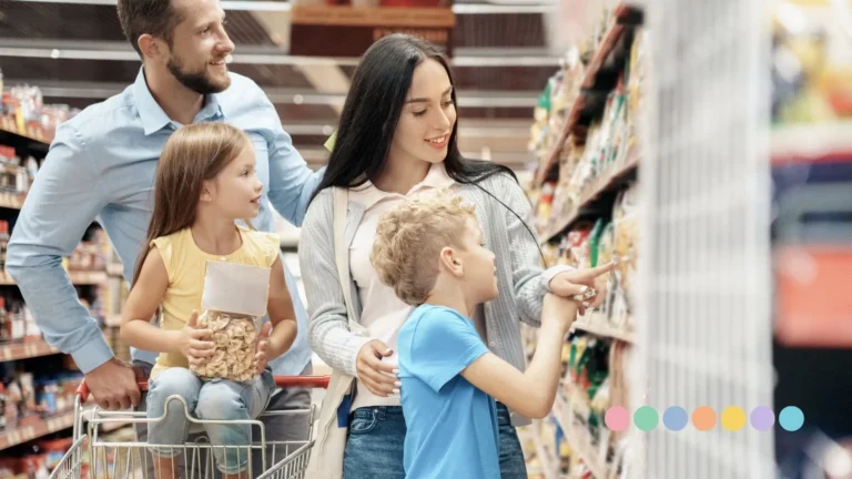Porodica sa dvoje dece bira proizvode u supermarketu, roditelji i deca zajedno učestvuju u kupovini i komunikaciji.