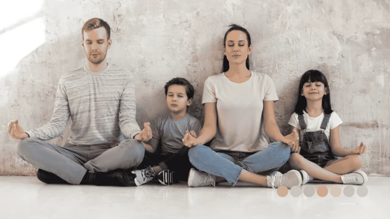 Četvoročlana porodica (majka, otac, sin i ćerka) sedi na podu uz betonski zid i meditira sa zatvorenim očima u položaju meditacije i opuštanja.